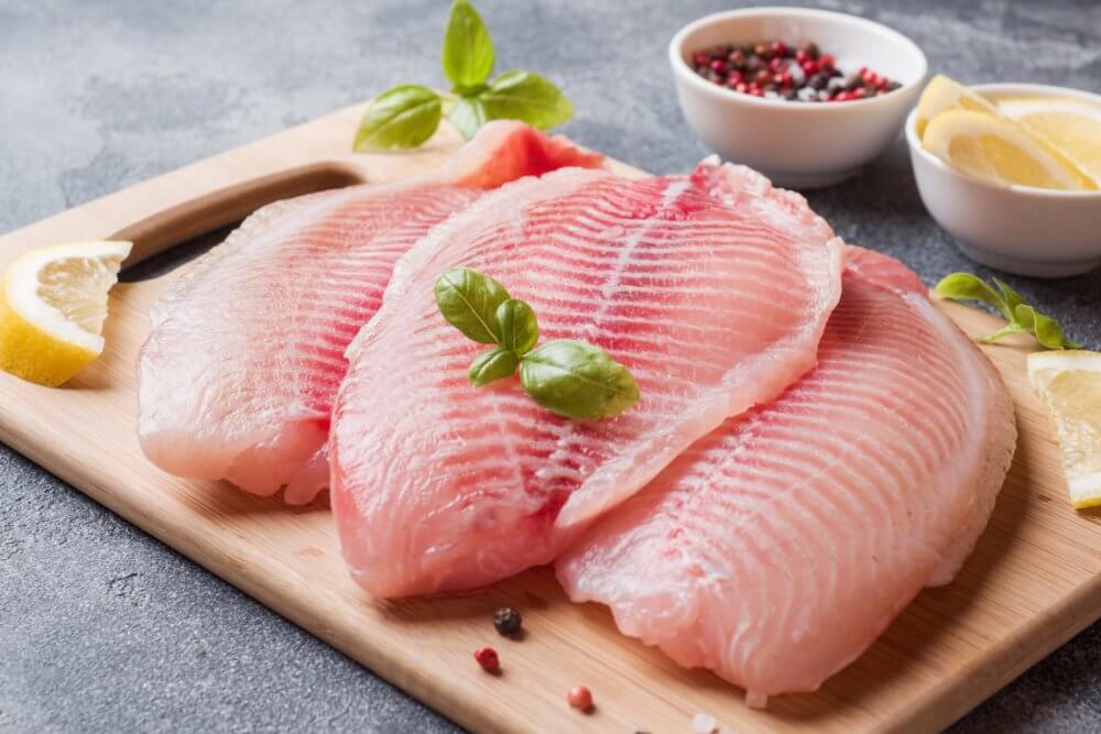 alimentos-con-mas-proteinas-filete-pescado-crudo-tilapia-tabla-cortar-limon-especias-mesa-oscura