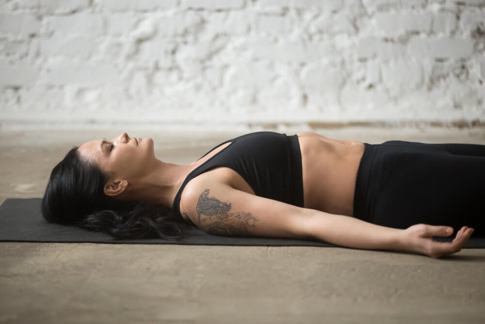 como-respirar-al-correrjoven-yogi-atractivo-mujer-savasana-pose-loft-plano-fondo